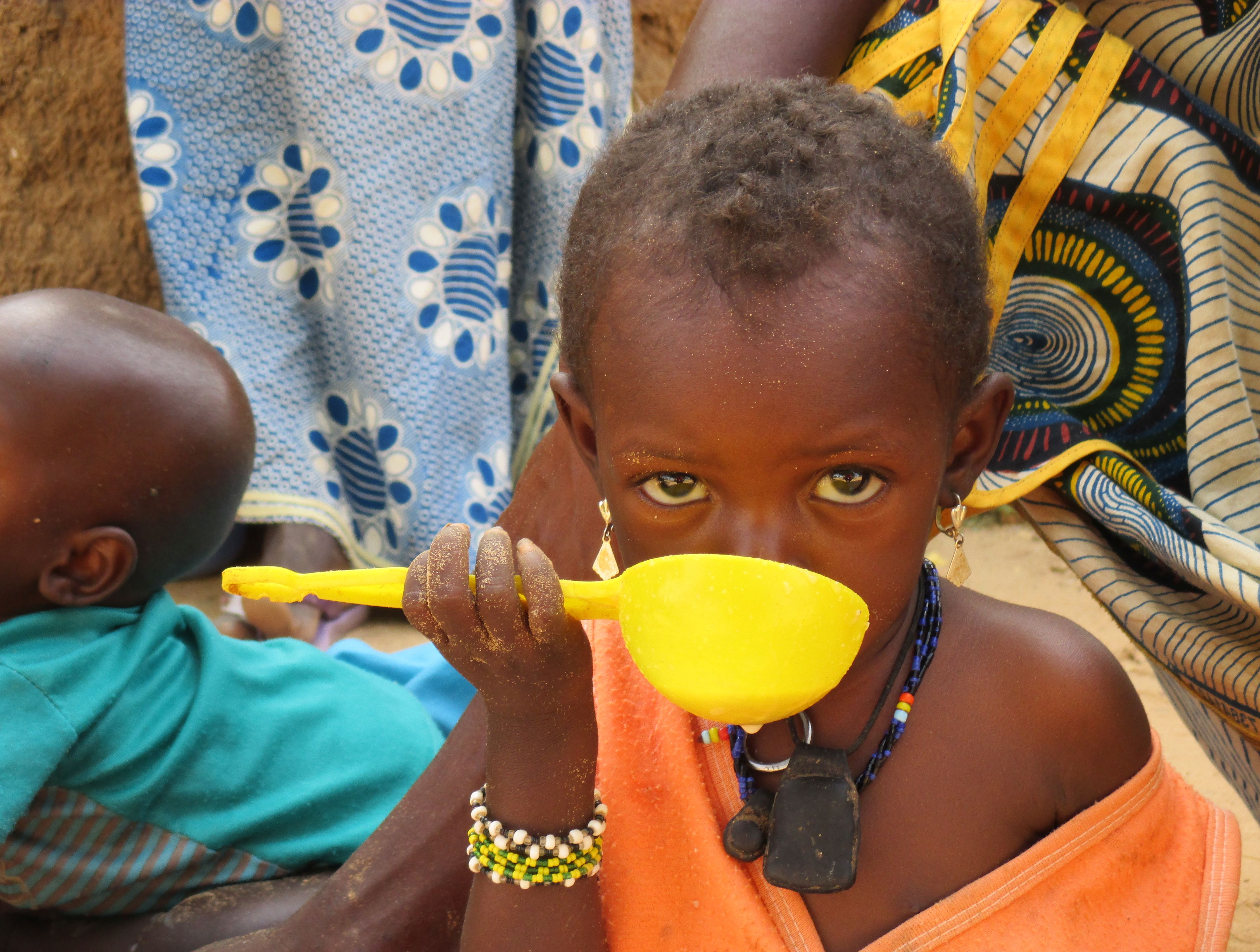 Foto meisje Niger eet meel uit plastieken pollepel
